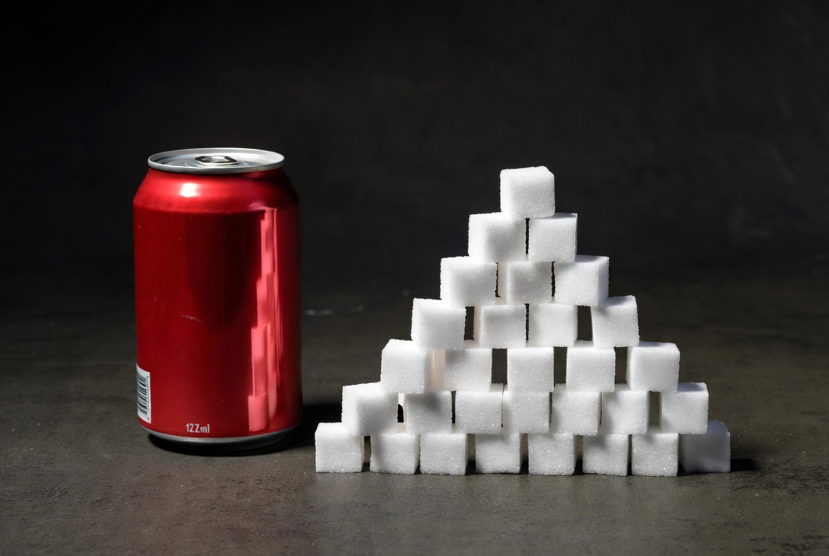 Sugar cubes piled next to soda can showing hidden sugar