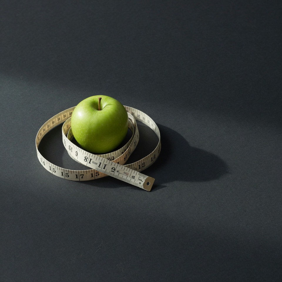 Measuring tape coiled around a green apple