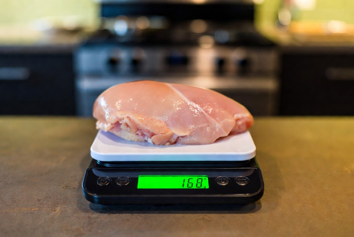 Digital food scale with chicken breast showing weight in grams