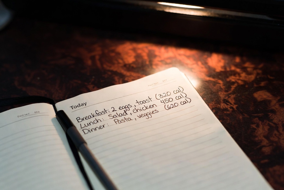 Handwritten food journal with pen on dark desk